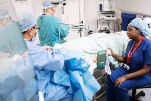 One of our Volunteers holding a patient's hand during an operation in the theatre.