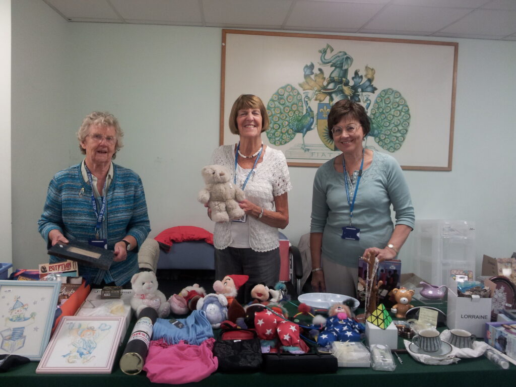 Volunteers standing behind a stall with toys and a bric-a-brac.