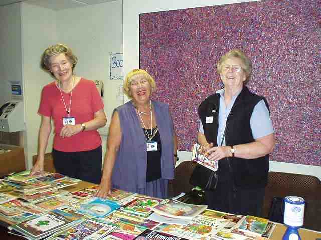 Volunteers standing behind a stall full of books.
