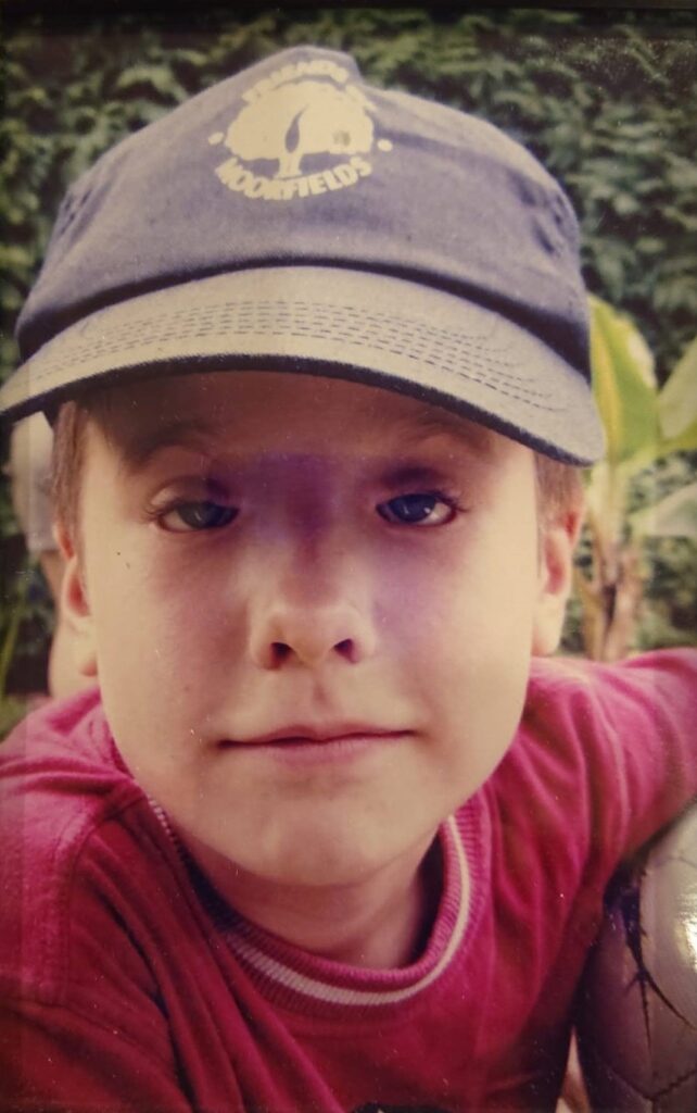 Felix poses looking at the camera, wearing a Friends of Moorfields baseball cap