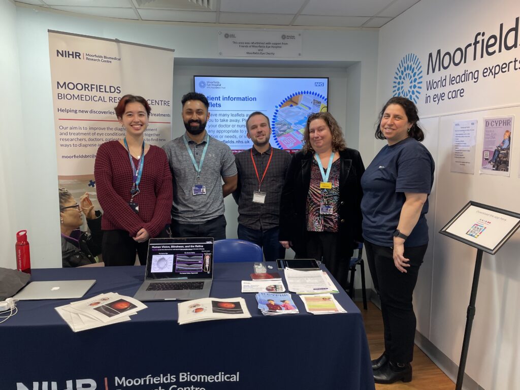A group of researchers pose smiling at the stand.
