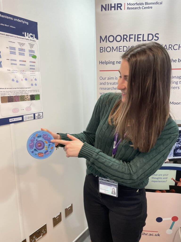 A researcher points to a diagram of a cell.