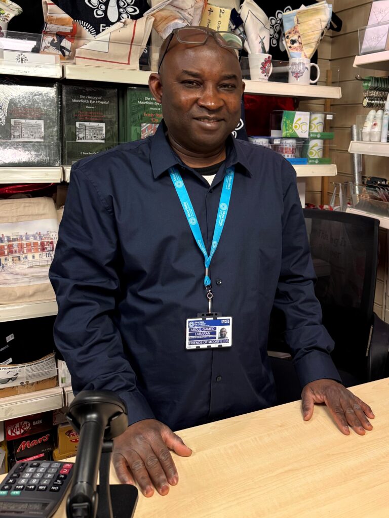 Abdul smiles behind the counter of the shop.