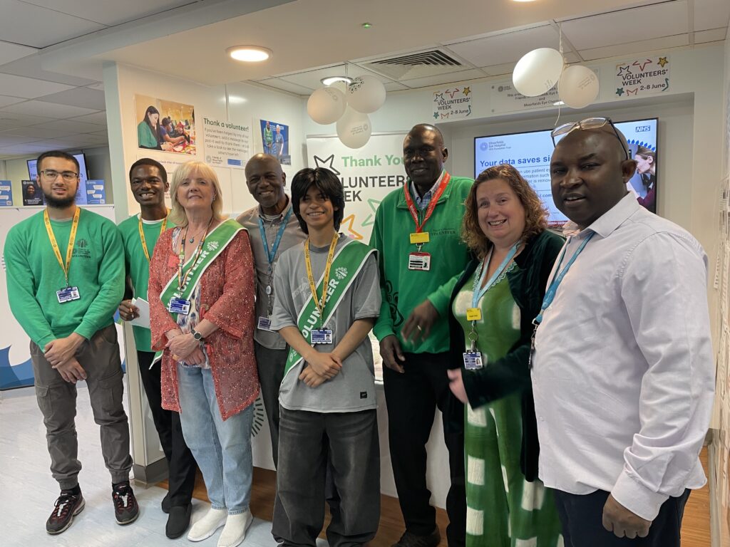 A group of staff and volunteers, including Angela, pose smiling together.
